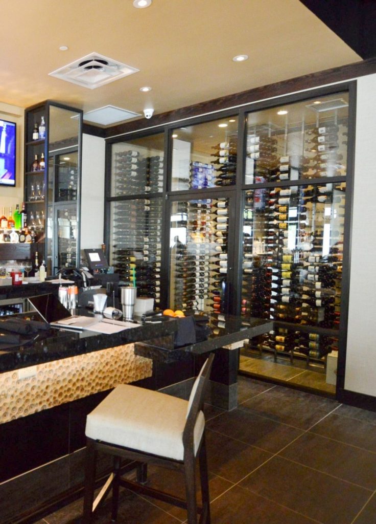 This contemporary commercial custom wine cellar in Dallas-Fort Worth, Texas, displays the wines in metal wine racks.
