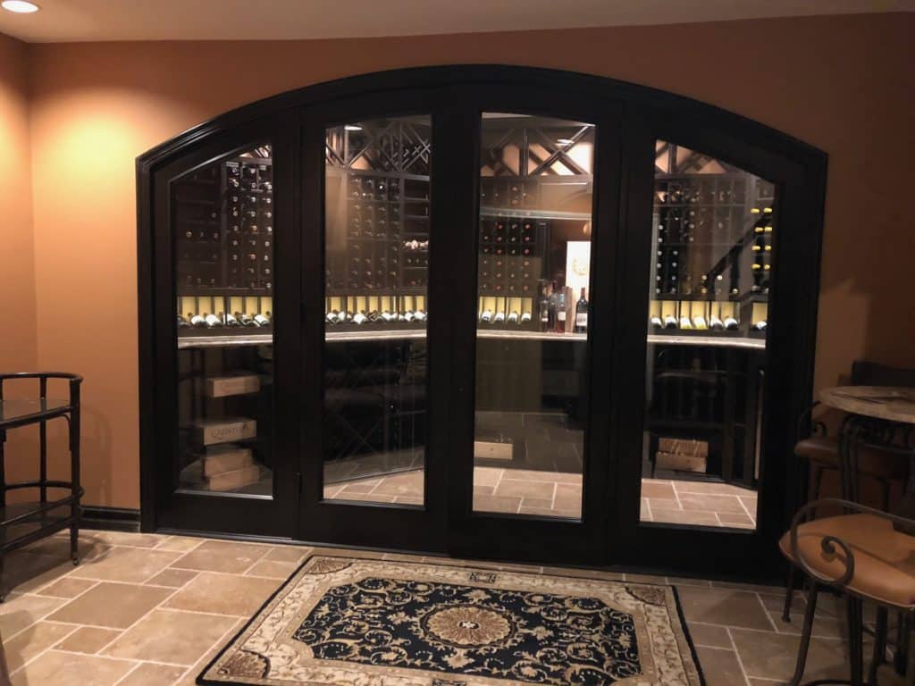 Custom, arched glass doors enclosing a gorgeous traditional home wine cellar.